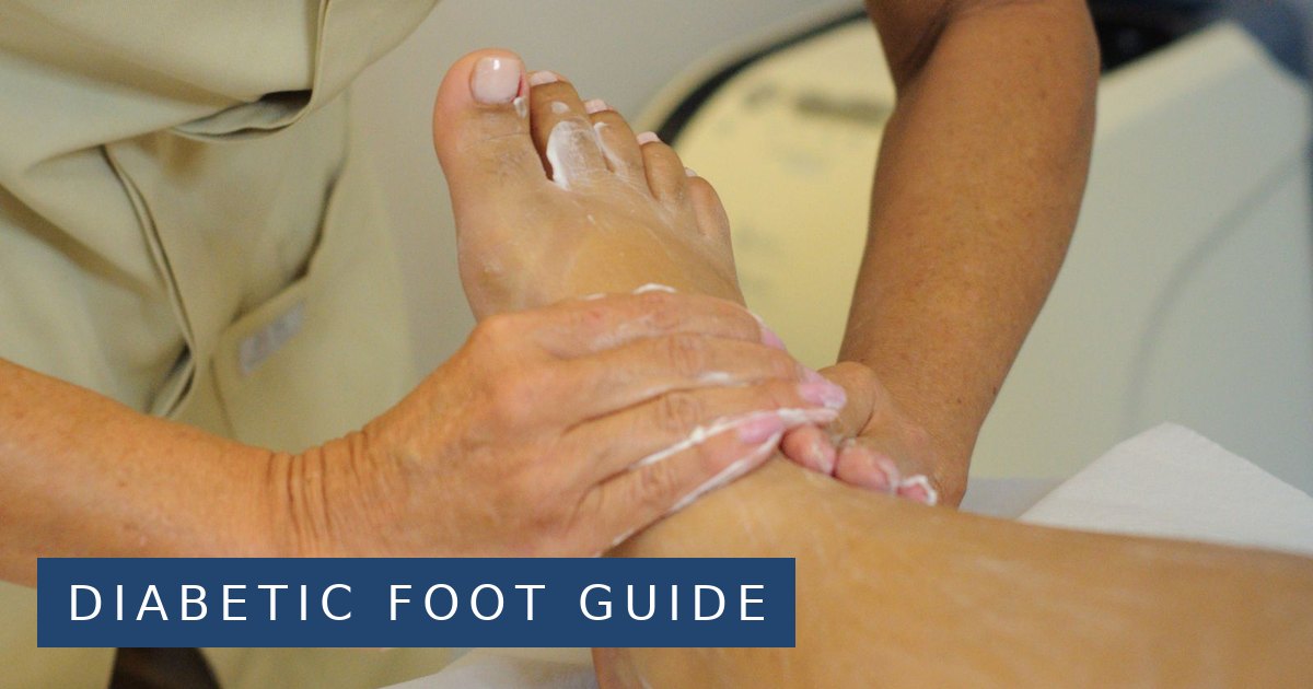 A therapist's hands massaging lotion into a client's foot